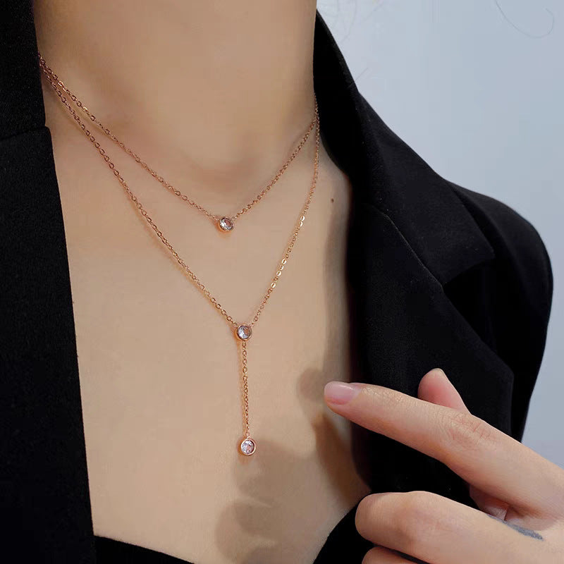 Rose gold necklace with small pink gemstones on a person wearing a black blazer.