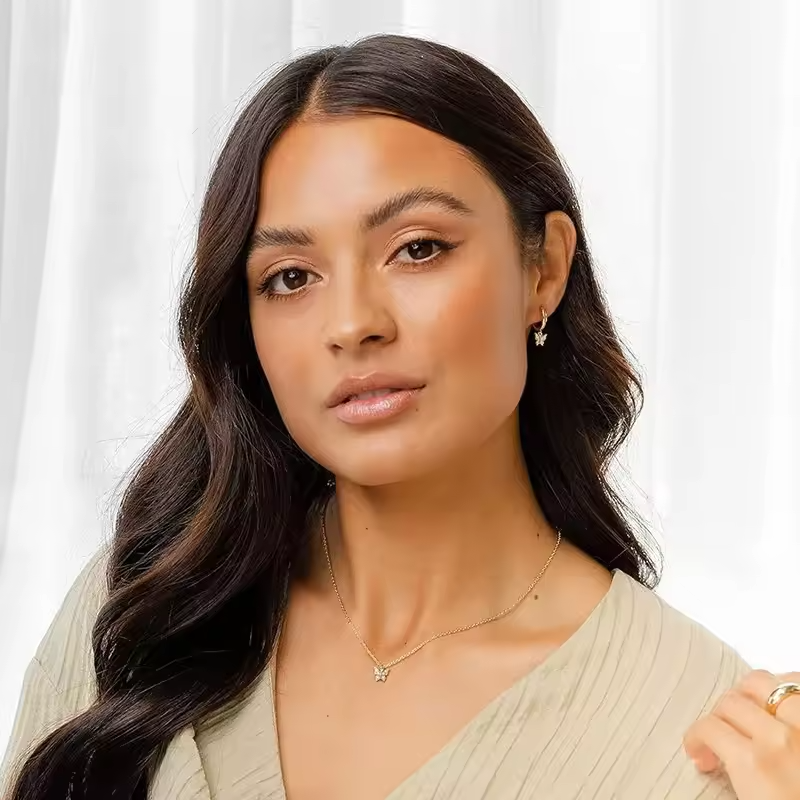 Woman wearing a necklace with a white curtain background
