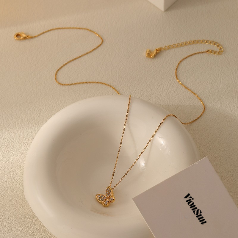 Gold necklace with a heart-shaped pendant on a white dish, with 'VionSun' branding visible.