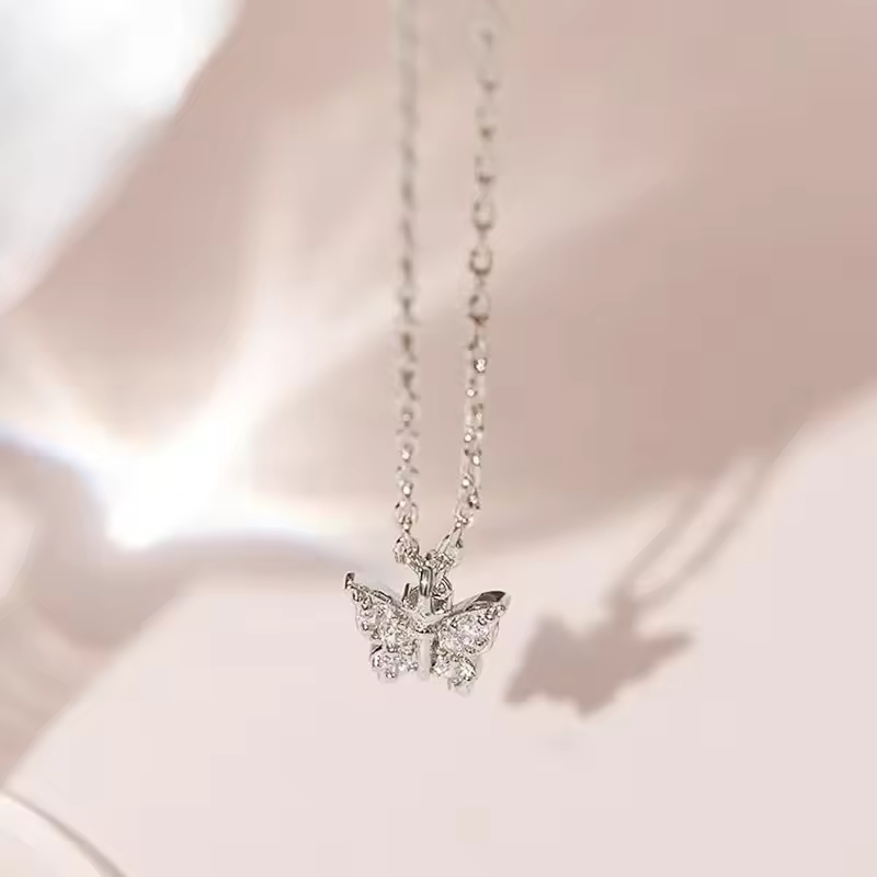 Silver butterfly necklace on a soft pink background