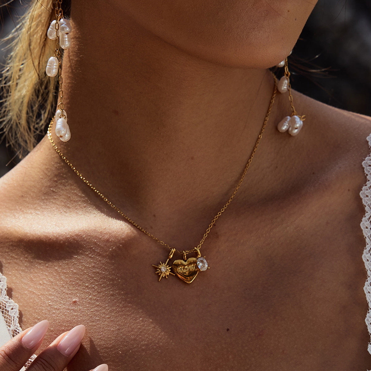 Close-up of a person wearing a gold necklace with a pendant, earrings, and a blurred background.