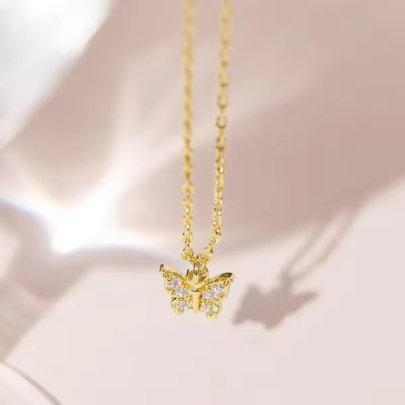 Gold butterfly necklace on a soft pink background