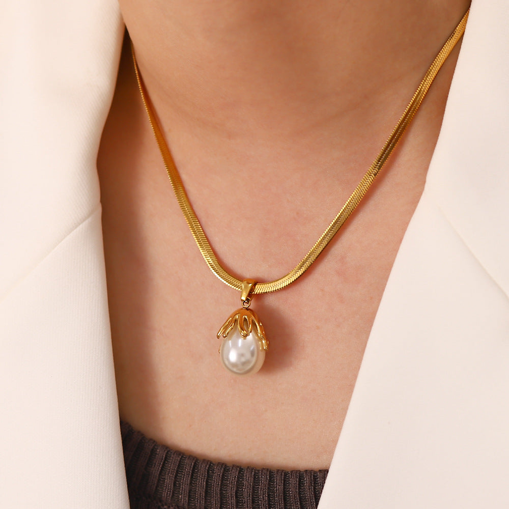 Gold necklace with a pearl pendant worn by a person